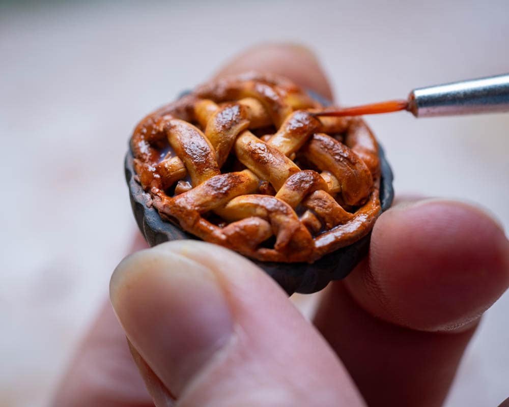 painting details on lattice pie crust A fine paint brush applying details on the lattice pie crust of a miniature pie
