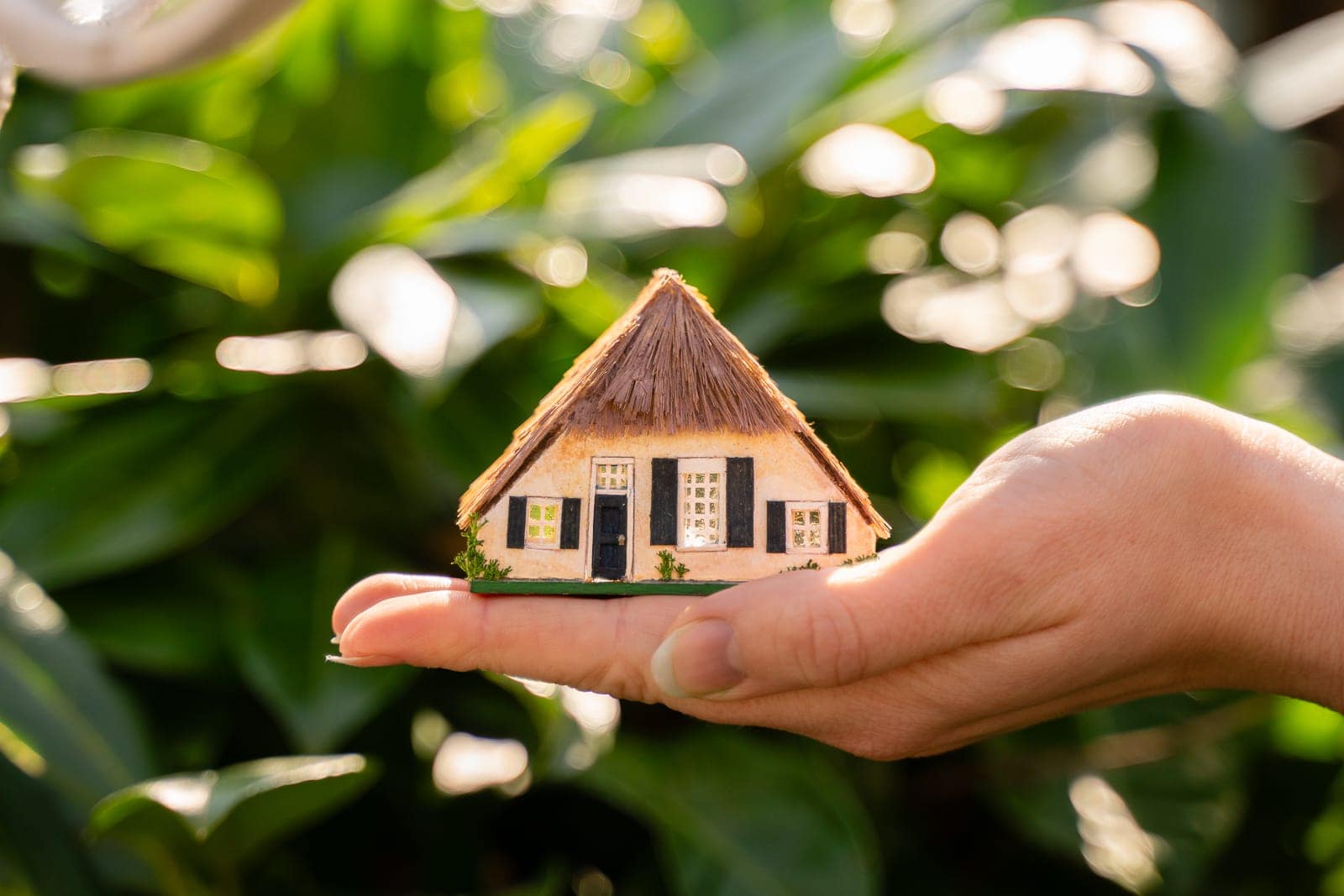 A hand holding a farmhouse made at 1/144 dollhouse scale
