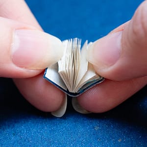 Four fingers flipping through a miniature book made with recycled paper