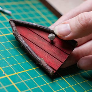 red triangular fairy door with nail doorknob An old nail repurposed to make a rustic doorknob for a red triangular fairy door