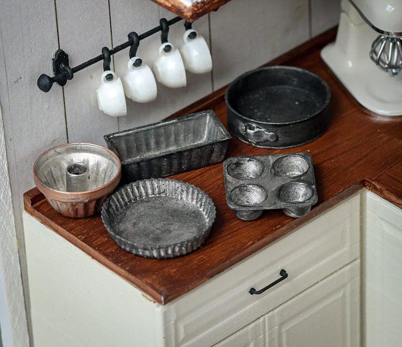 A set of miniature clay pans on a miniature kitchen counter